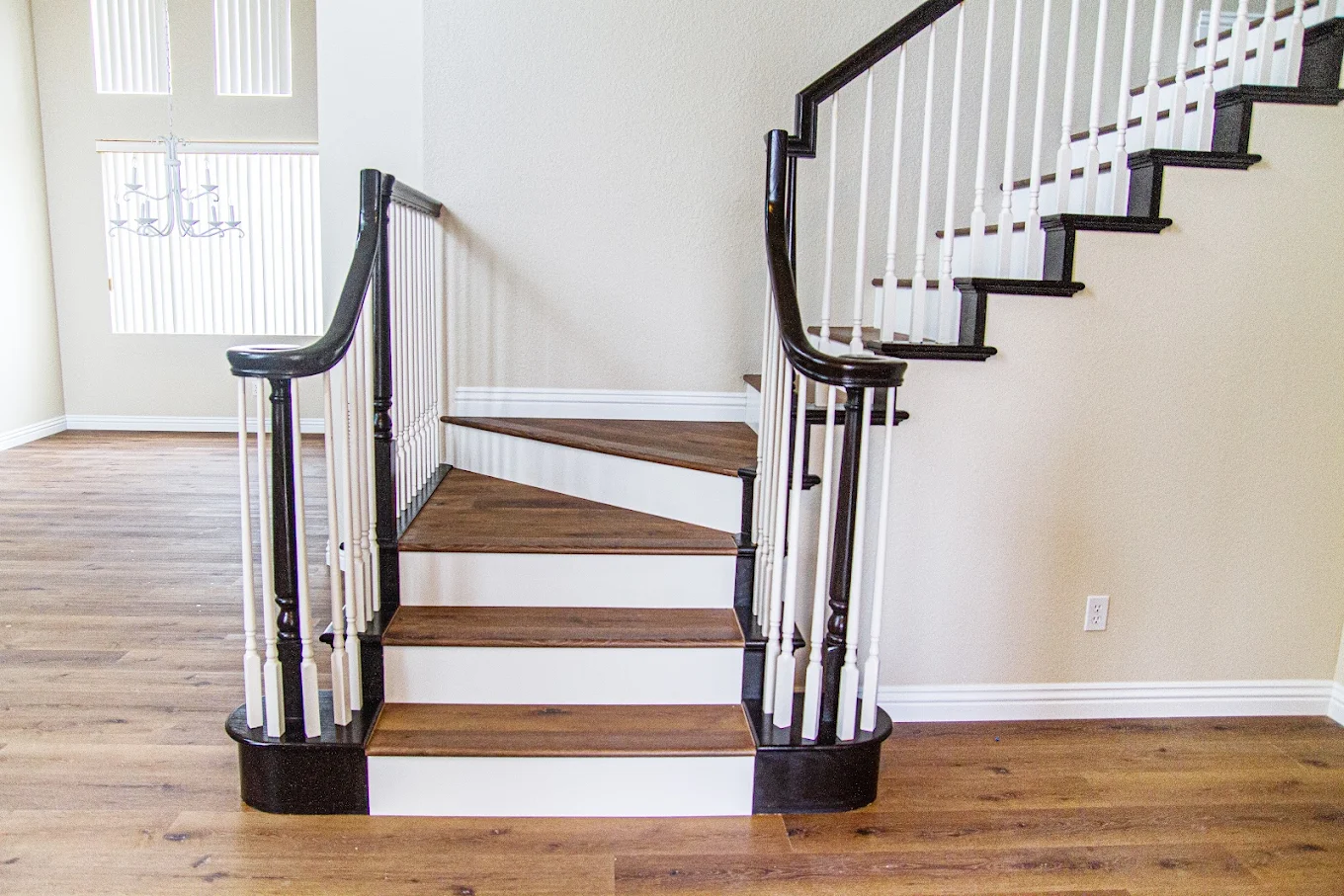Staircase with wood-look treads and white risers beside a dark wood railing, over a matching wood floor